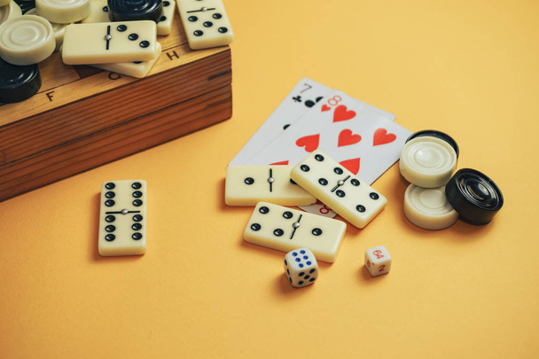 Various board games chess board, playing cards, dominoes on a orange background. - 写真・画像