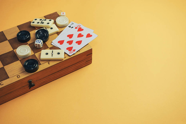 Diverse bordspellen schaakbord, speelkaarten, dominostenen op een oranje achtergrond. - Foto, afbeelding
