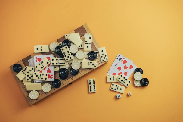 Diverse bordspellen schaakbord, speelkaarten, dominostenen op een oranje achtergrond. - Foto, afbeelding