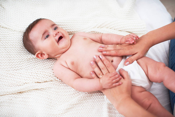 Masseur massaging the tummy of the baby during colic - Φωτογραφία, εικόνα