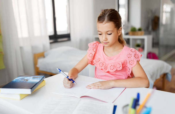 student girl with book writing to notebook at home - Foto, Imagen
