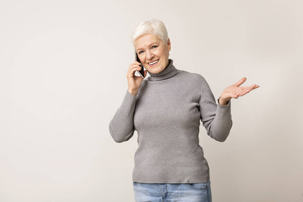 Aantrekkelijke oudere vrouw aan het praten op mobiele telefoon - Foto, afbeelding