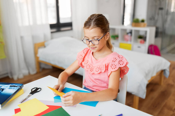 girl with color paper sitting at table at home - Photo, image