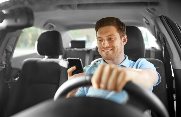 man driving car and using smartphone - Foto, afbeelding