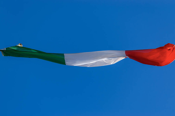 Italian lippu vilkuttaa kirkkaalla sinisellä taivaalla - Pohjannäkymä
 - Valokuva, kuva