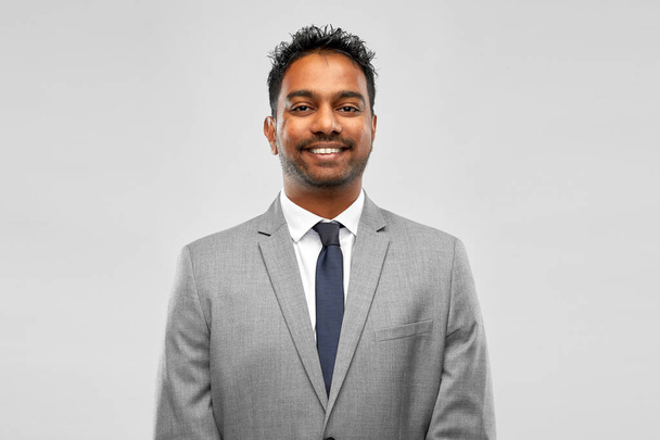 smiling indian businessman over grey background - Fotoğraf, Görsel