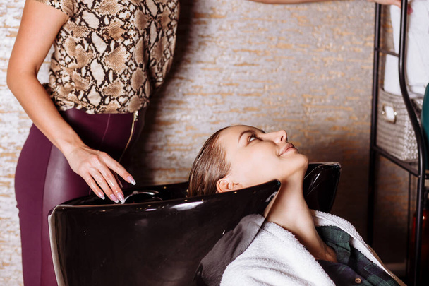 Beautiful woman washing hair in a hair salon - Фото, зображення
