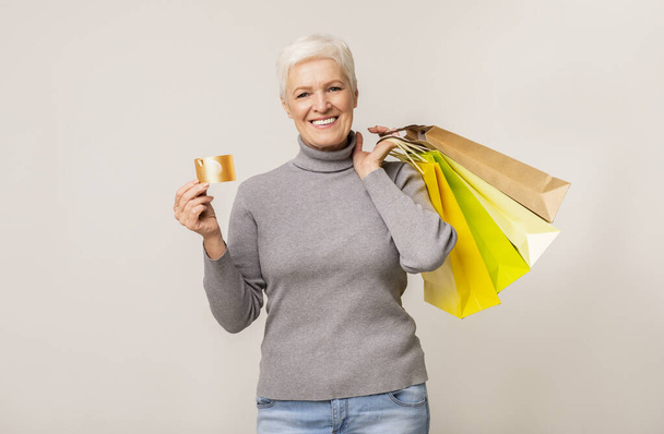 Gyönyörű idős hölgy bevásárlótáskákkal és hitelkártyával - Fotó, kép