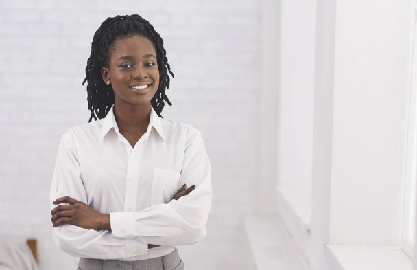 Smiling Afro Business Girl Standing Crossing Hands Against White Wall - Photo, Image