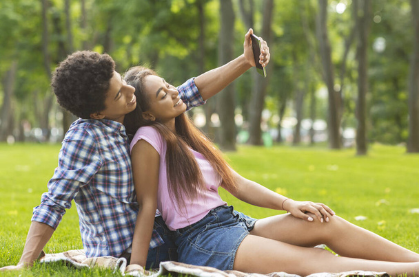 Couple of teenagers taking selfie on picnic outdoors - Photo, Image