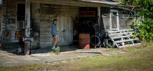 Jonge tiener staande op verlaten tankstation - Foto, afbeelding