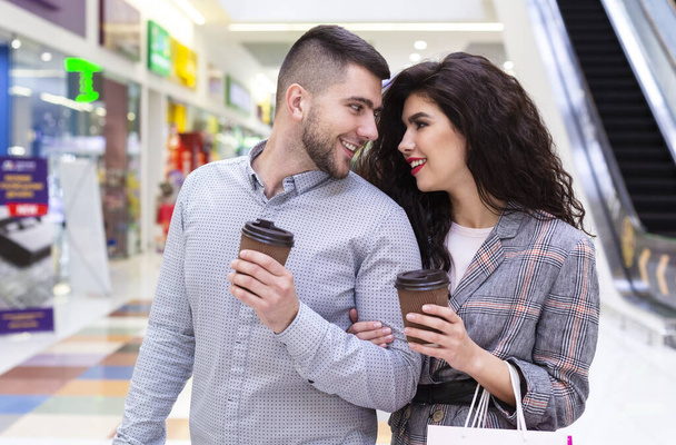 Loving couple with coffee to go walking by shopping mall - Zdjęcie, obraz