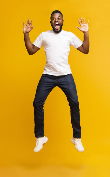 Surpreendido afro-americano saltando de braços erguidos e gritando
 - Foto, Imagem