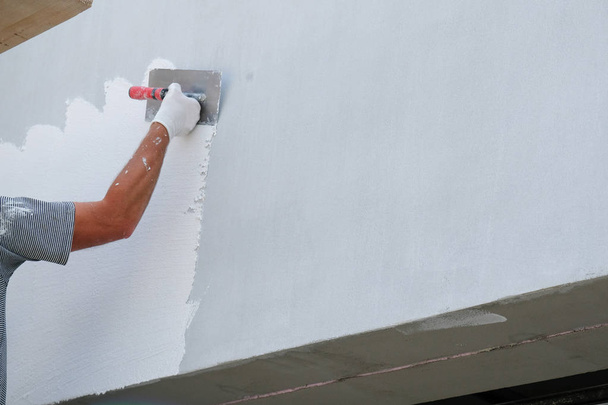 Painter applying fresh paint on the house facade - 写真・画像