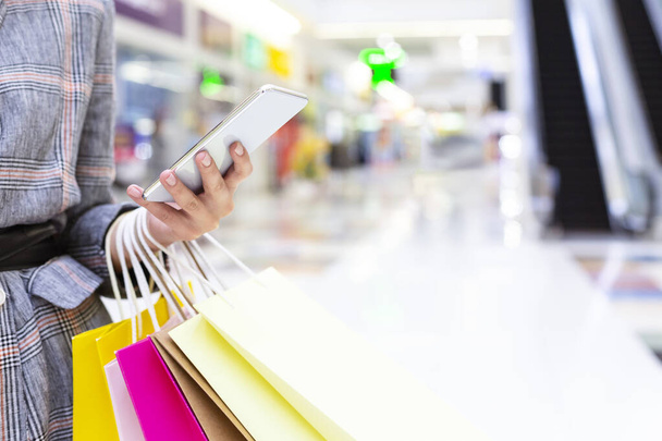 Concepto de compras. Mujer usando smartphone en gran centro comercial
 - Foto, Imagen