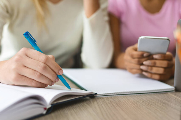 Adolescente escrevendo notas no caderno, estudando com amigos ao ar livre
 - Foto, Imagem