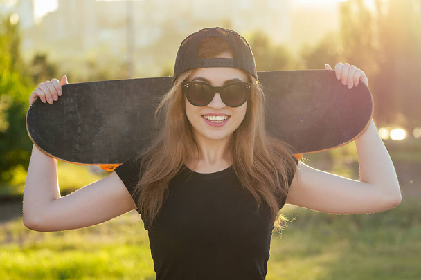 young cool girl holding a skateboard in a skatepark - Фото, изображение