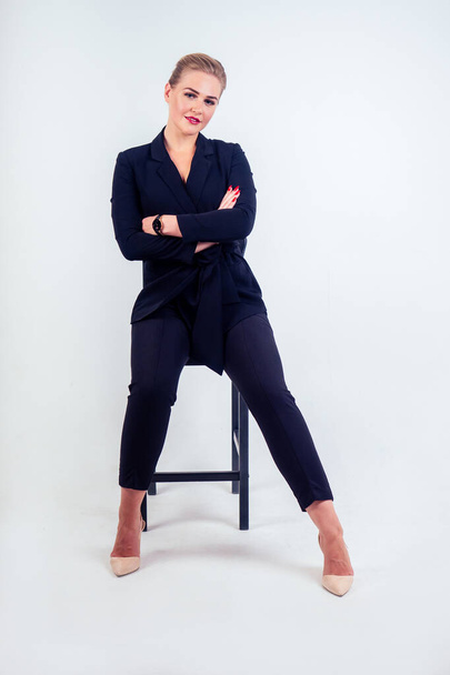 Full length portrait of successful business woman glasses blonde hairstyle perfect make-up red lips in stylish black suit , fashion high heel shoes sitting on a chair studio white isolate. - Photo, image