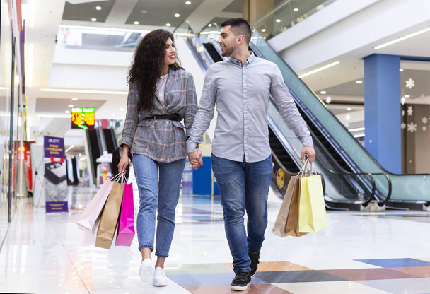 Happy millennial couple walking after shopping in mall - Photo, Image