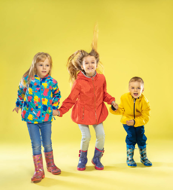 A full length portrait of a bright fashionable kids in a raincoat - Foto, afbeelding