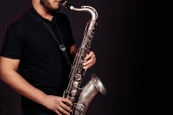 El joven toca el saxofón. De cerca.
 - Foto, imagen