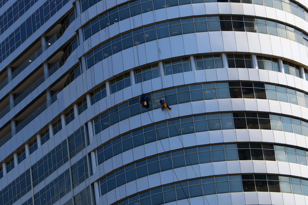 İşçiler İsrail 'in büyük bir şehrindeki yüksek bir binanın camlarını silerler.  - Fotoğraf, Görsel