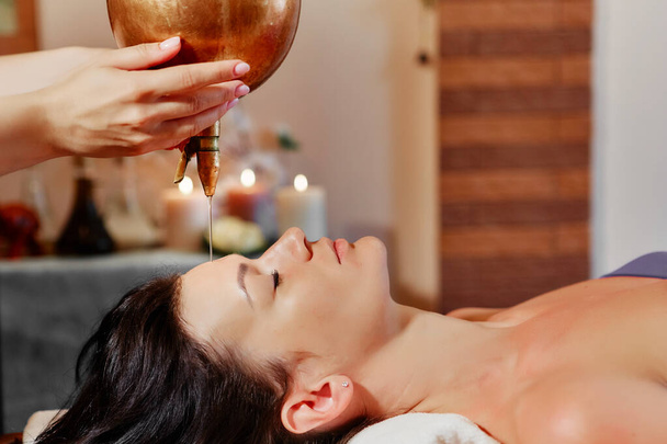 a unique Ayurvedic procedure Shirodhara that elevates you to a state called trance. The flow of pleasant sensations covers your entire body, you relax both physically and spiritually. The procedure - Foto, Imagem