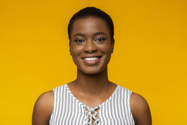 Портрет улыбающейся чёрной женщины на жёлтом фоне
 - Фото, изображение