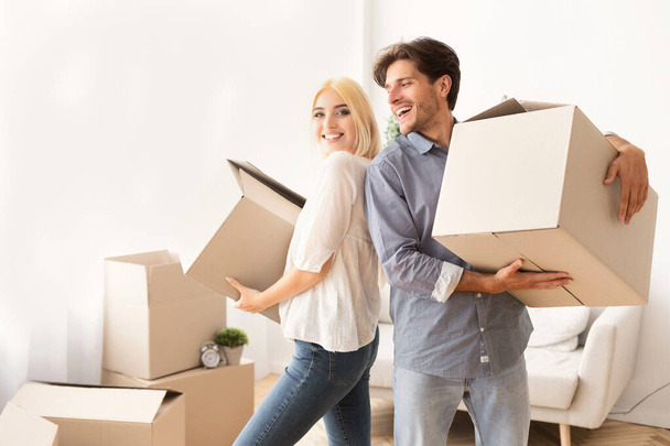 Счастливые супруги держат коробки, стоящие в новом доме
 - Фото, изображение