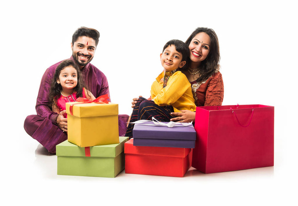 Indian family celebrating Diwali / Deepavali in traditional wear while sitting isolated over white background with gift boxes and lamp in thali - Fotoğraf, Görsel