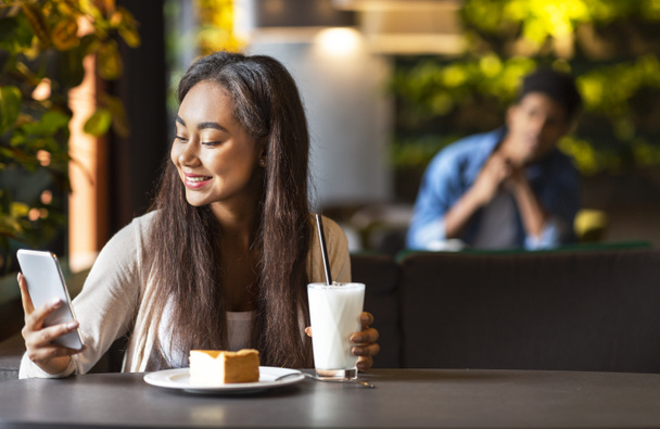 Молода красива дівчина використовує додаток для знайомств в кафе
 - Фото, зображення