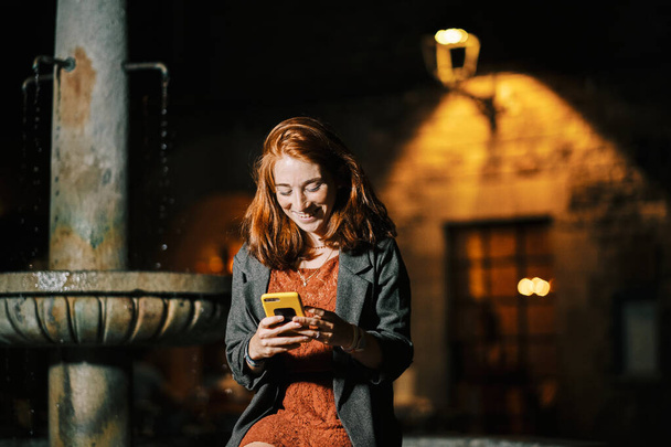 San Felip Neri広場、バルセロナ、若い女の子は夜に携帯電話を読む - 写真・画像