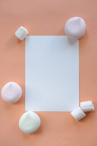 Leeg papier over pastel Kleurrijke marshmallow en oranje achtergrond. Zoet ongezond voedsel. Blanco vel voor poster, banner, design. Zwijg. - Foto, afbeelding