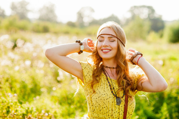 Sonriente chica bohemia en vestido amarillo con guitarra en el campo al atardecer
 - Foto, imagen