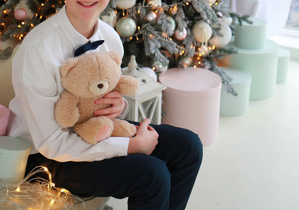 fiú egy dobozzal és egy medve ül egy újévi kanapén  - Fotó, kép