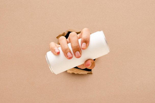 The hand hold a can through the broken wall  - Valokuva, kuva