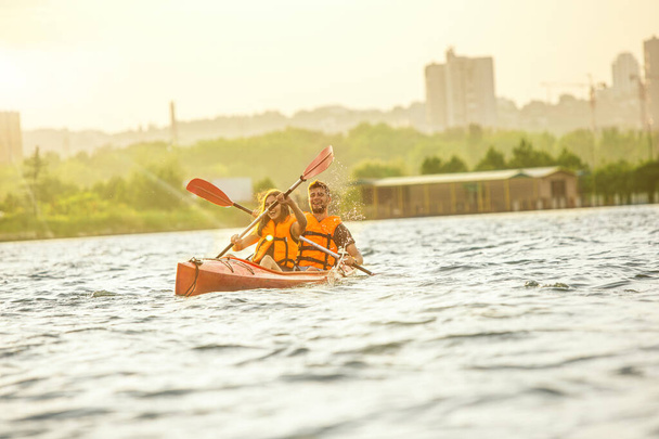 Happy couple kayaking on river with sunset on the background - Foto, Imagen