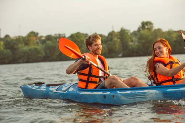 Happy couple kayaking on river with sunset on the background - Foto, immagini