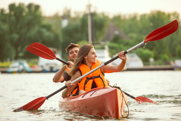 Happy couple kayaking on river with sunset on the background - Photo, Image