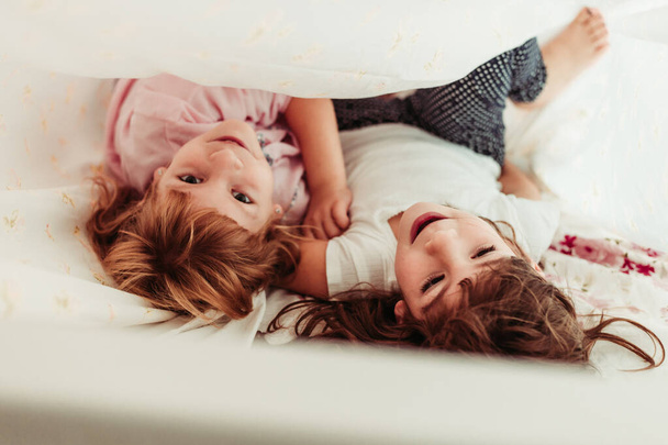 Γλυκά κοριτσάκια, αδερφές να ξυπνάνε το πρωί. Παιδιά με πιτζάμες, κοιμούνται. - Φωτογραφία, εικόνα