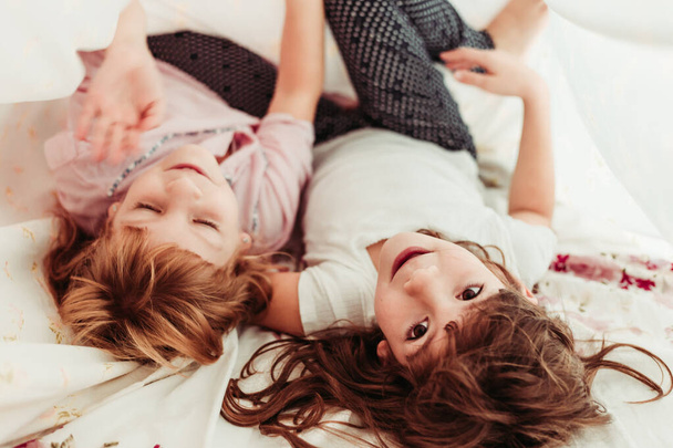 Cute little girls, sisters waking up in the morning. Kids in pajamas, sleeping - Fotografie, Obrázek