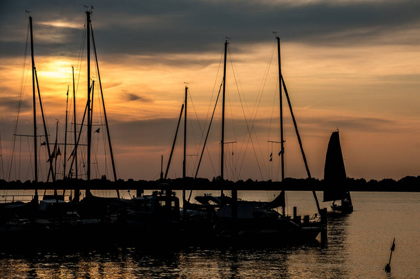 Petit havre de paix avec voiliers et coucher de soleil doré
 - Photo, image