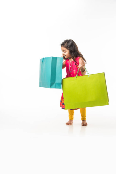 Indiai kislány gazdaság bevásárló táskák, álló elszigetelt felett fehér háttér - Fotó, kép