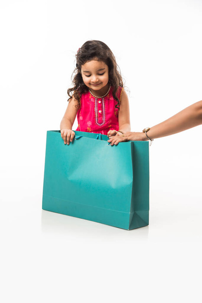 India niña pequeña sosteniendo bolsas de compras, de pie aislado sobre fondo blanco
 - Foto, imagen