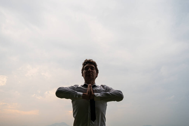 Giovane uomo d'affari che medita sotto il cielo nuvoloso
 - Foto, immagini