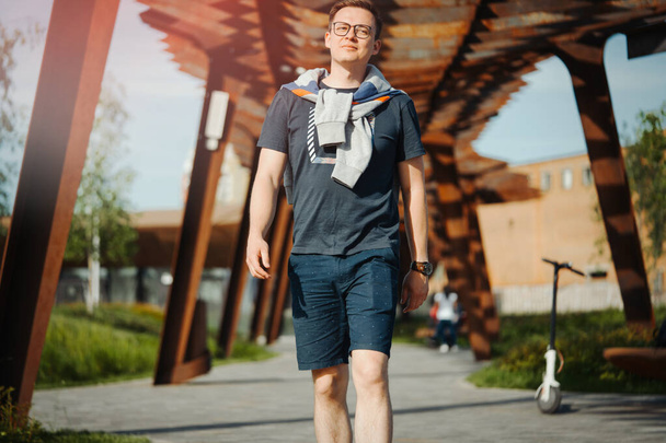 Attractive man strolling at modern park. Man is on foreground, modern park is on background. - Fotoğraf, Görsel