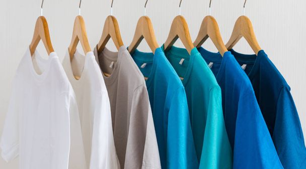 Крупный план красочных футболок на вешалках, на фоне одежды
 - Фото, изображение