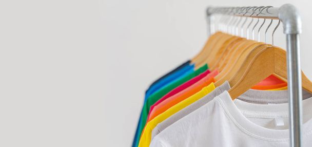 Nahaufnahme von bunten T-Shirts auf Kleiderbügeln, Bekleidungshintergrund - Foto, Bild