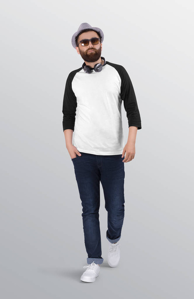 Περπάτημα γενειοφόρος σε λευκό και μαύρο plain 2 / 3 μανίκι raglan πουκάμισο φορώντας μπλε τζιν παντελόνι τζιν. απομονωμένο υπόβαθρο. - Φωτογραφία, εικόνα