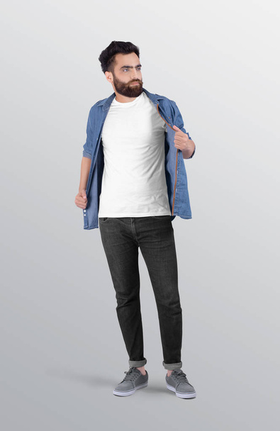 Мужчина в белой простой футболке на шее команды в темно-серых джинсах в джинсах, с джинсовой рубашкой сверху. изолированный фон
. - Фото, изображение